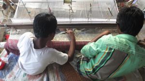 Weavers weaving by child